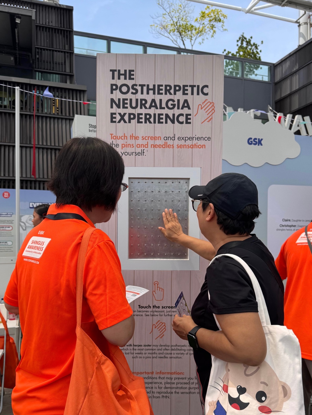 A shingles awareness community ambassador (left) demonstrates a simulation of long-term pain or postherpetic neuralgia (PHN), a potential complication of shingles.11 Photo: GSK.